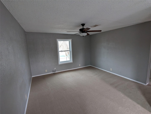 carpeted spare room with a textured ceiling, a ceiling fan, visible vents, and baseboards