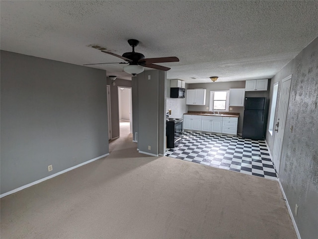 kitchen featuring light floors, a sink, visible vents, white cabinetry, and black appliances