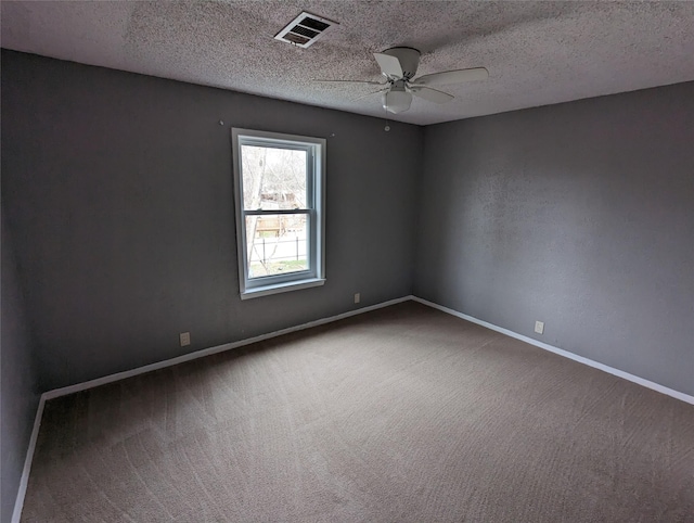 spare room with carpet, visible vents, a ceiling fan, a textured ceiling, and baseboards