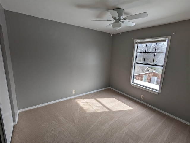 carpeted spare room with a ceiling fan and baseboards