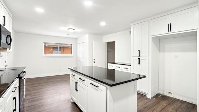 kitchen featuring black microwave, dark countertops, dark wood-style floors, and white cabinets