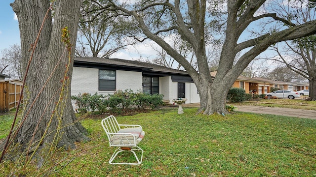 view of front facade featuring brick siding, a front lawn, and fence