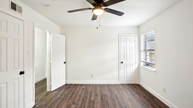 unfurnished bedroom with a ceiling fan, dark wood-style flooring, visible vents, and baseboards