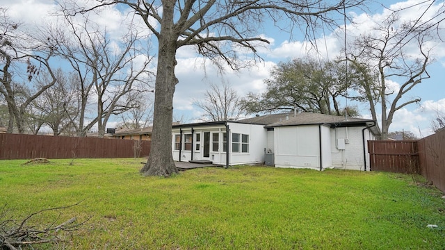 back of house featuring brick siding, a lawn, and a fenced backyard