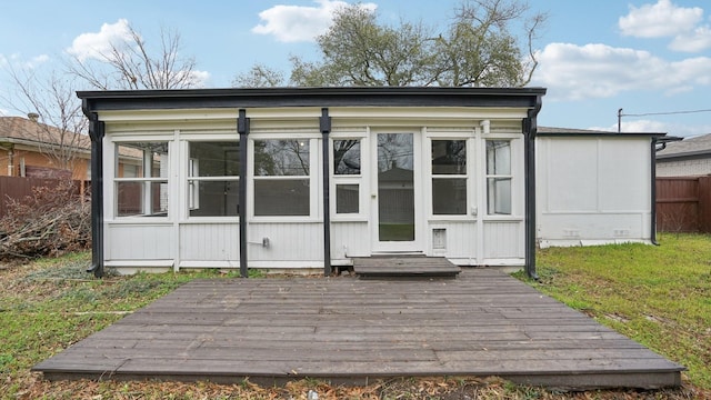 view of outdoor structure with a sunroom and fence