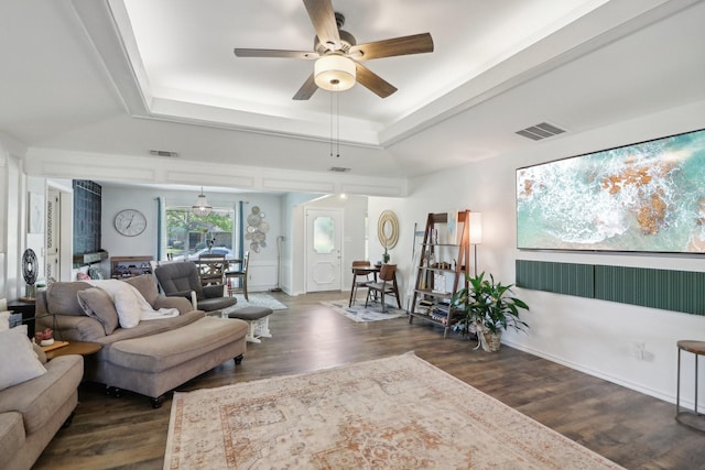 living area featuring dark wood-style floors, a tray ceiling, and visible vents