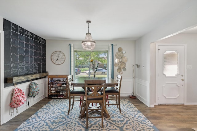 dining area with a chandelier, a wainscoted wall, and wood finished floors