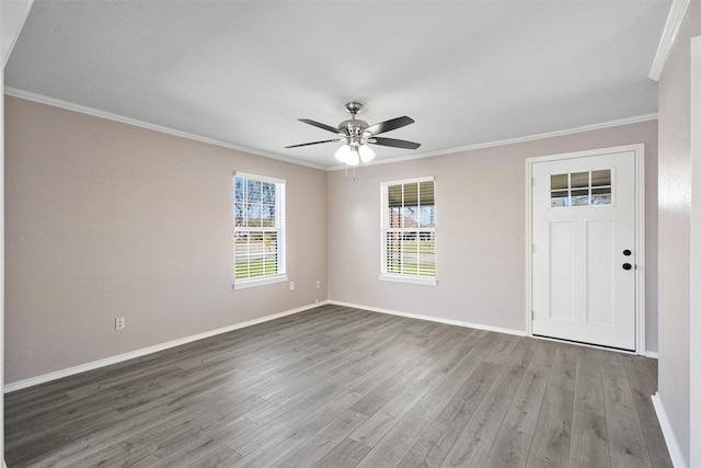 interior space featuring baseboards, wood finished floors, ornamental molding, and a ceiling fan