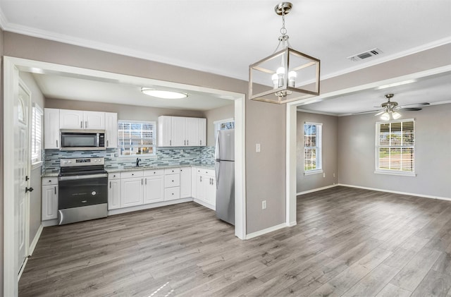 kitchen featuring decorative backsplash, light wood-style flooring, open floor plan, and appliances with stainless steel finishes