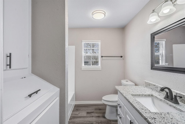 full bathroom with vanity, wood finished floors, toilet, and a healthy amount of sunlight