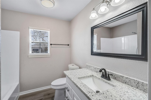 full bath with baseboards, toilet, wood finished floors, a textured wall, and vanity