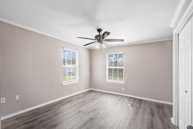 unfurnished bedroom with ceiling fan, baseboards, ornamental molding, wood finished floors, and a closet