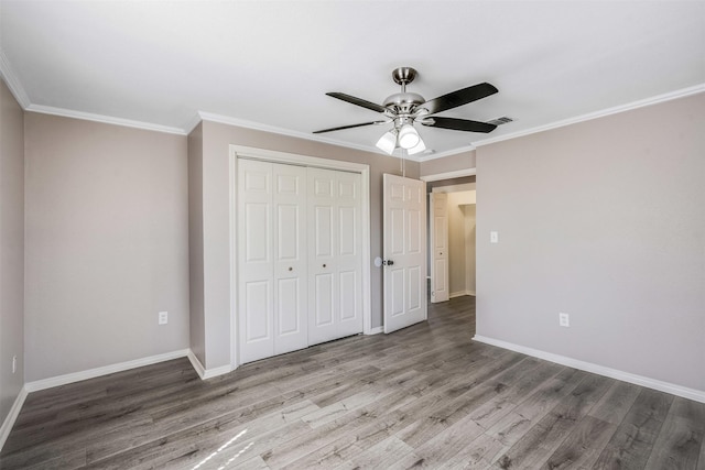 unfurnished bedroom featuring a ceiling fan, wood finished floors, baseboards, a closet, and crown molding