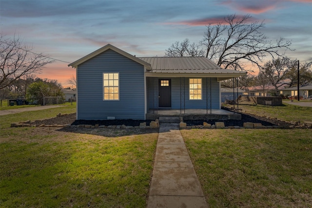 view of front of home with metal roof, covered porch, and a front lawn