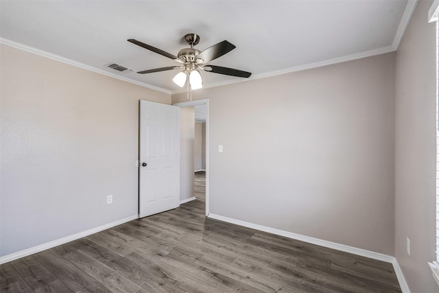 spare room featuring visible vents, baseboards, wood finished floors, and crown molding