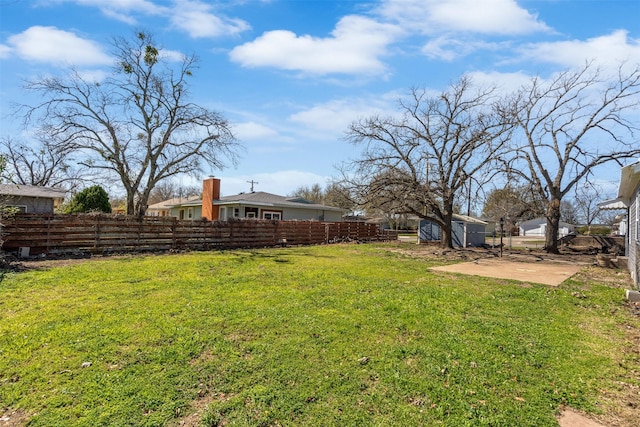 view of yard featuring a patio area, an outbuilding, and fence