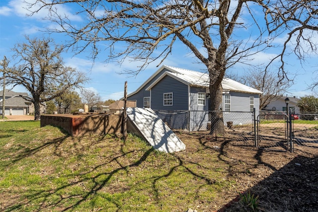 view of side of home featuring metal roof, fence, a yard, and a gate