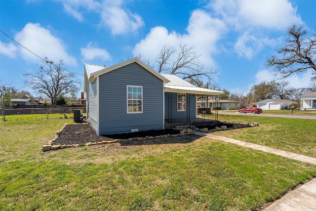 view of property exterior featuring metal roof, central AC unit, a lawn, and fence