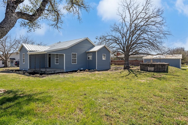 rear view of house featuring a lawn, metal roof, and fence