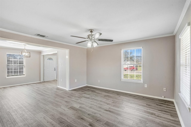 empty room featuring visible vents, ornamental molding, baseboards, and wood finished floors