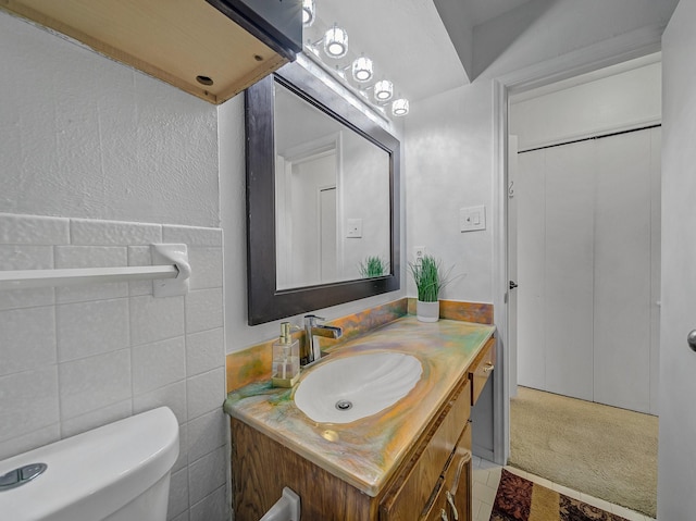 half bathroom featuring toilet, vanity, and tile walls