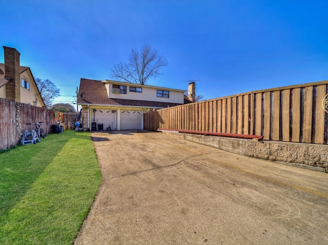 back of house featuring a garage, roof with shingles, a lawn, and fence