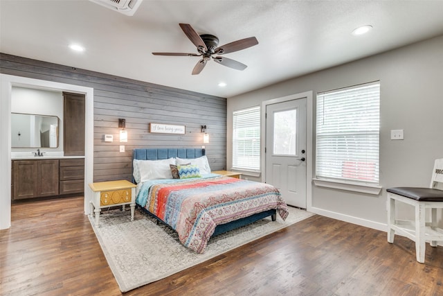 bedroom with recessed lighting, a sink, wood walls, and wood finished floors