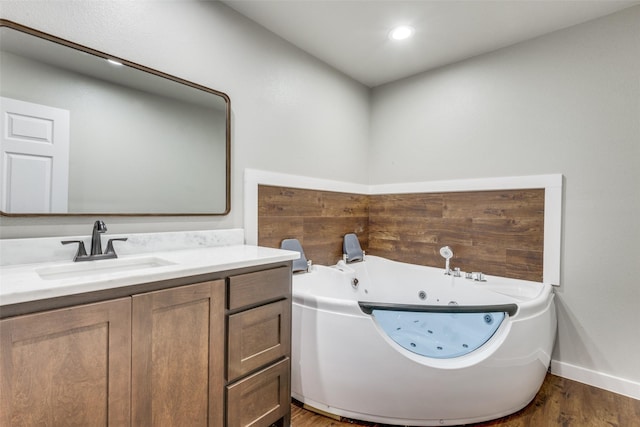 bathroom featuring recessed lighting, wood finished floors, vanity, baseboards, and a whirlpool tub