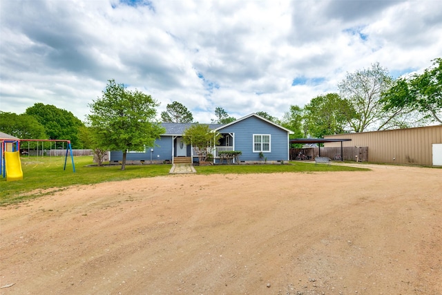 back of house with dirt driveway, crawl space, fence, a playground, and a carport