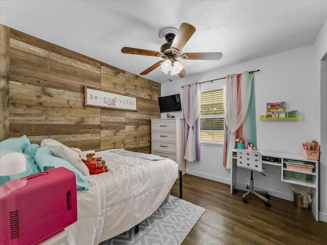 bedroom featuring ceiling fan, wood walls, baseboards, and wood finished floors