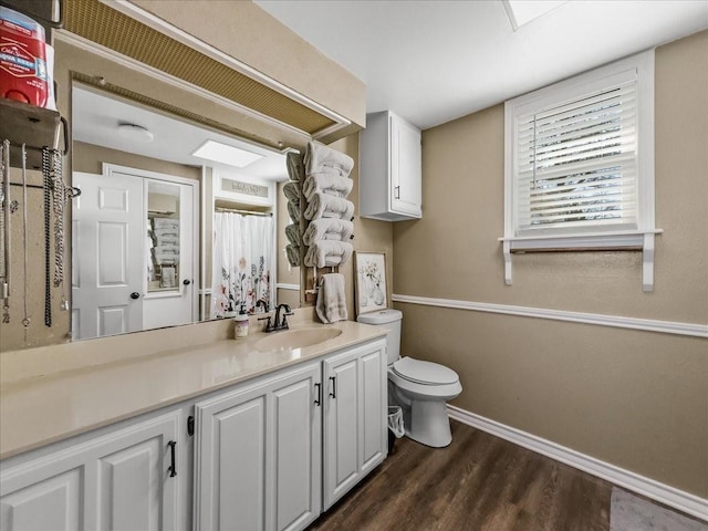 bathroom with toilet, vanity, wood finished floors, a shower with curtain, and baseboards