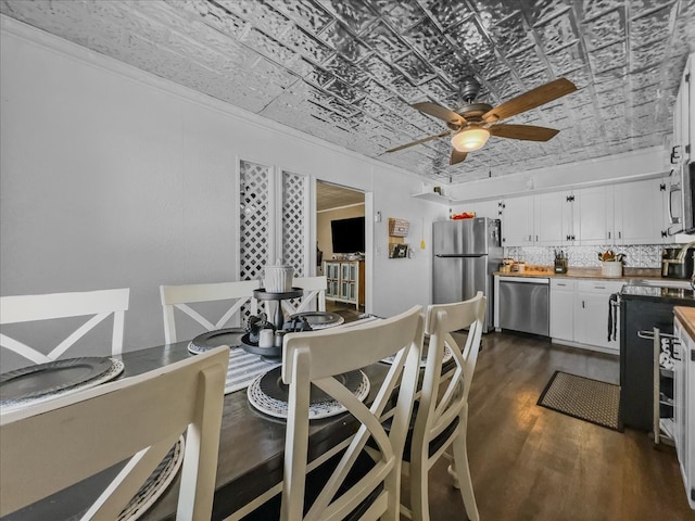 dining area with an ornate ceiling, crown molding, dark wood finished floors, and ceiling fan