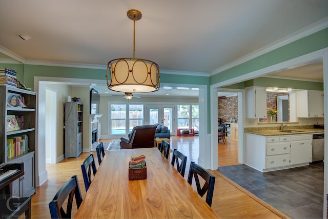 dining room with a fireplace, ornamental molding, and wood finished floors