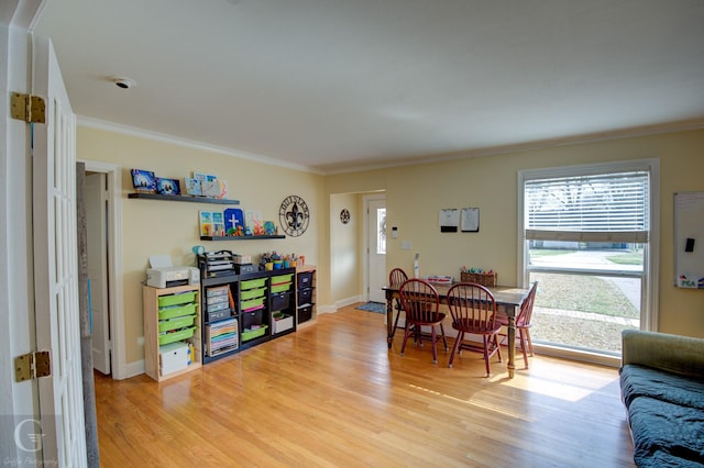 dining area featuring light wood-type flooring, baseboards, and crown molding