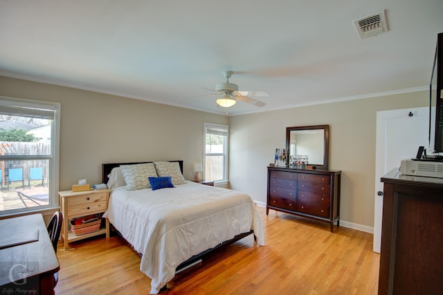 bedroom with baseboards, light wood-style flooring, visible vents, and crown molding