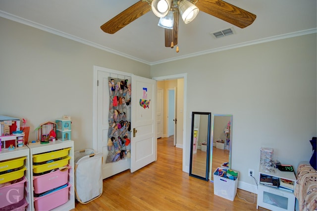 rec room with crown molding, visible vents, ceiling fan, wood finished floors, and baseboards