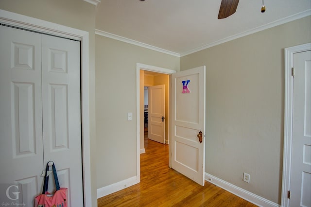 unfurnished bedroom featuring light wood-style flooring, a ceiling fan, baseboards, a closet, and crown molding