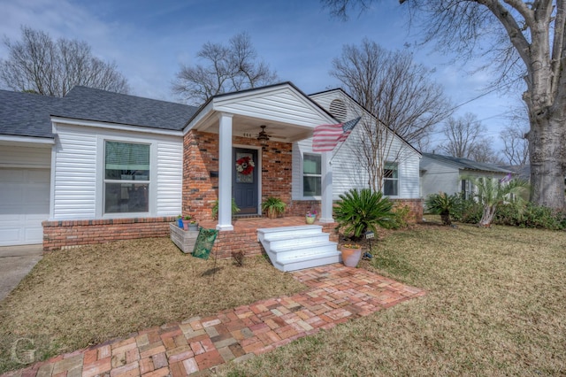 view of front of property featuring roof with shingles, brick siding, a front lawn, and a ceiling fan