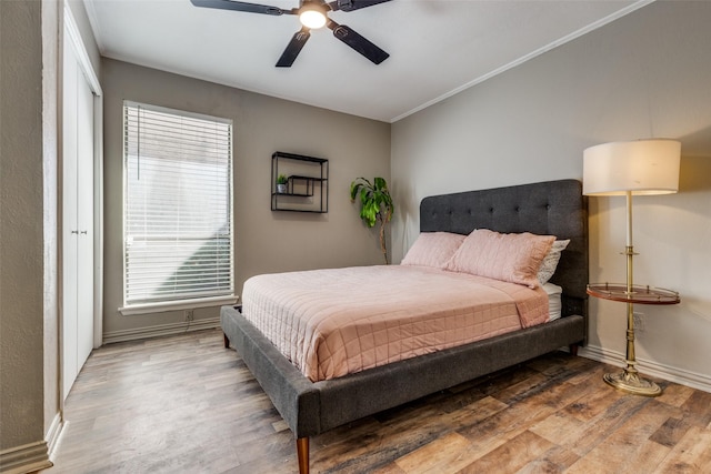 bedroom featuring ceiling fan, ornamental molding, wood finished floors, and baseboards