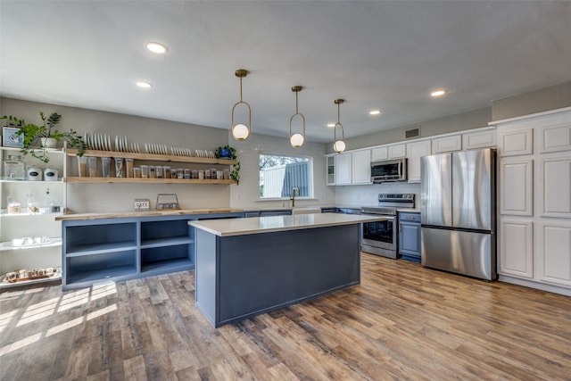 kitchen with wood finished floors, open shelves, appliances with stainless steel finishes, and light countertops