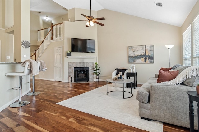 living area featuring visible vents, high vaulted ceiling, wood finished floors, ceiling fan, and stairs