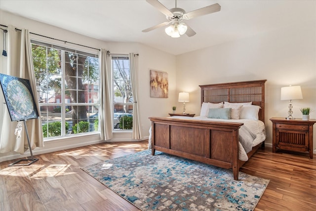 bedroom with baseboards, multiple windows, and wood finished floors