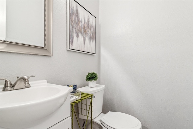 half bath with toilet, vanity, and a textured wall