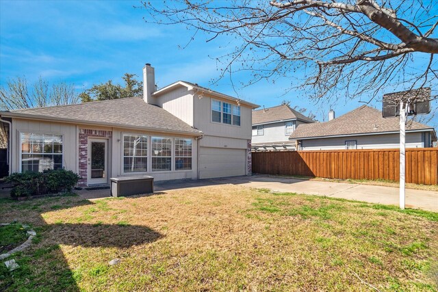 rear view of house featuring fence, concrete driveway, a lawn, a chimney, and a garage