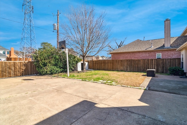 view of yard featuring a fenced backyard, an outbuilding, a storage shed, and a patio area