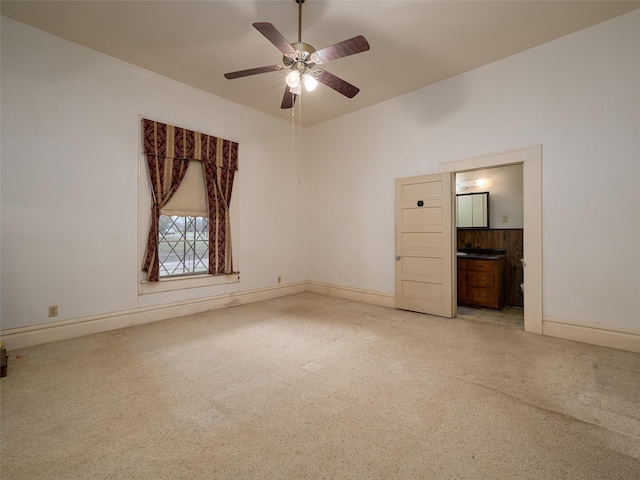 spare room with light colored carpet, ceiling fan, and baseboards