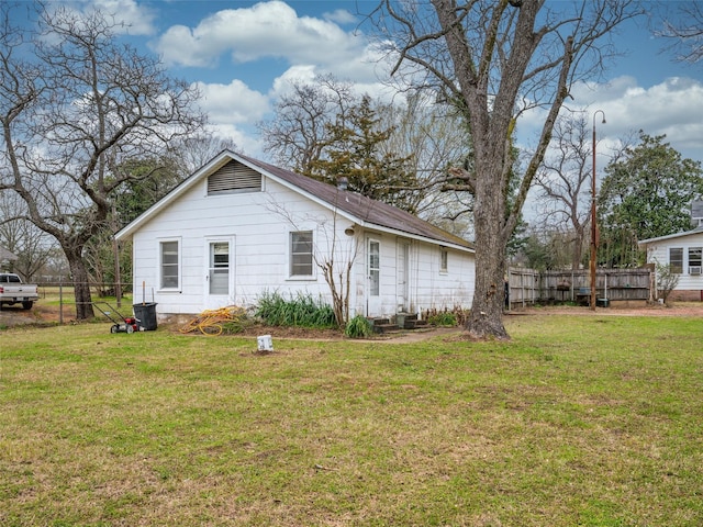 view of side of home featuring fence and a lawn