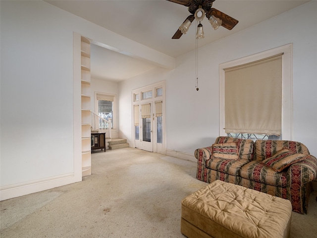 carpeted living area with ceiling fan and beam ceiling