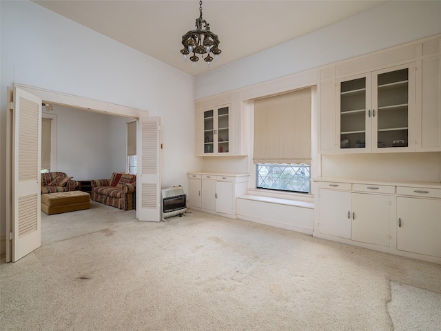 interior space with an inviting chandelier, heating unit, and light colored carpet