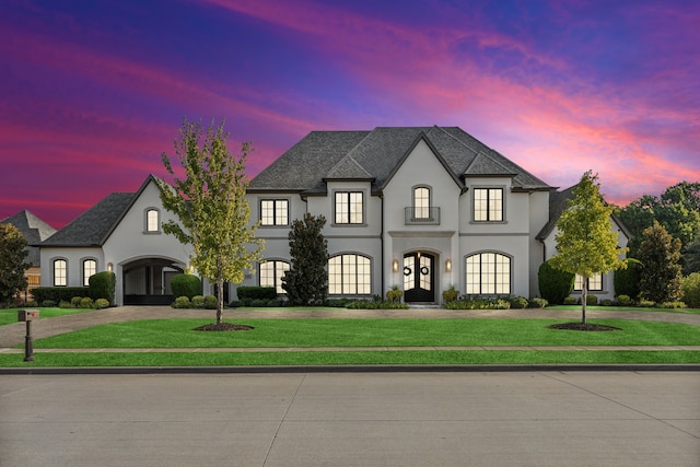 french country style house featuring a front yard, french doors, curved driveway, and stucco siding